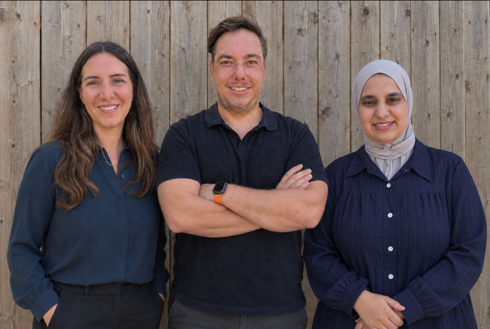 Dinah Zacher, Jürgen Zacher und Malika El Bachiri, das Team von Therese Blau, vor einer Holzwand.